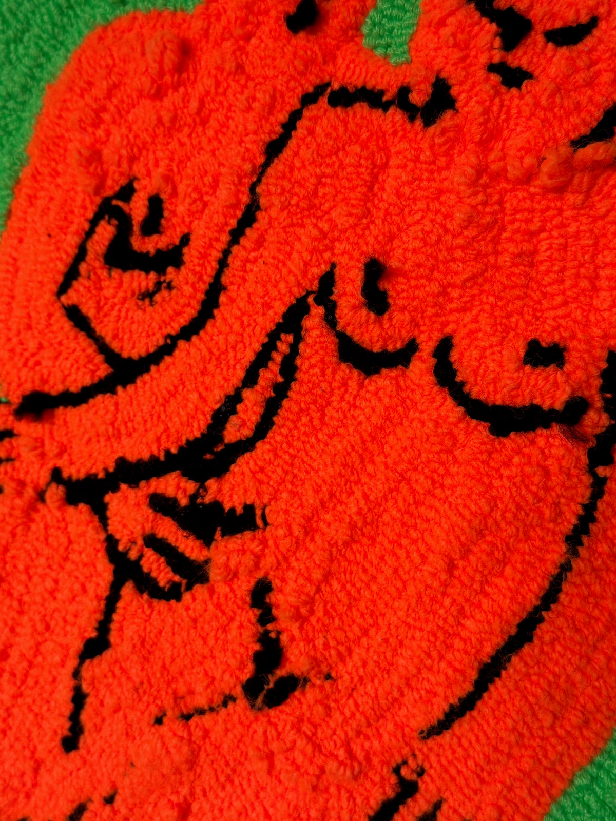 Close-up of a red fabric with black embroidered design on a green background