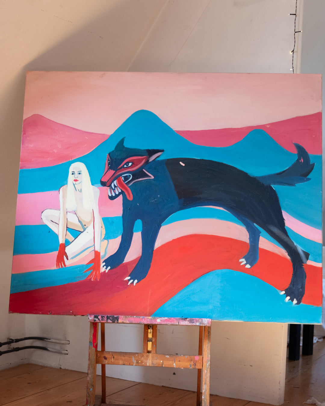 Colorful abstract painting on an easel with a woman and a creature against a striped background.