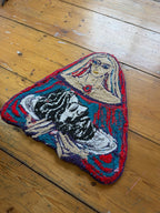 Decorative wall tapestry with a stylized face design on a wooden floor