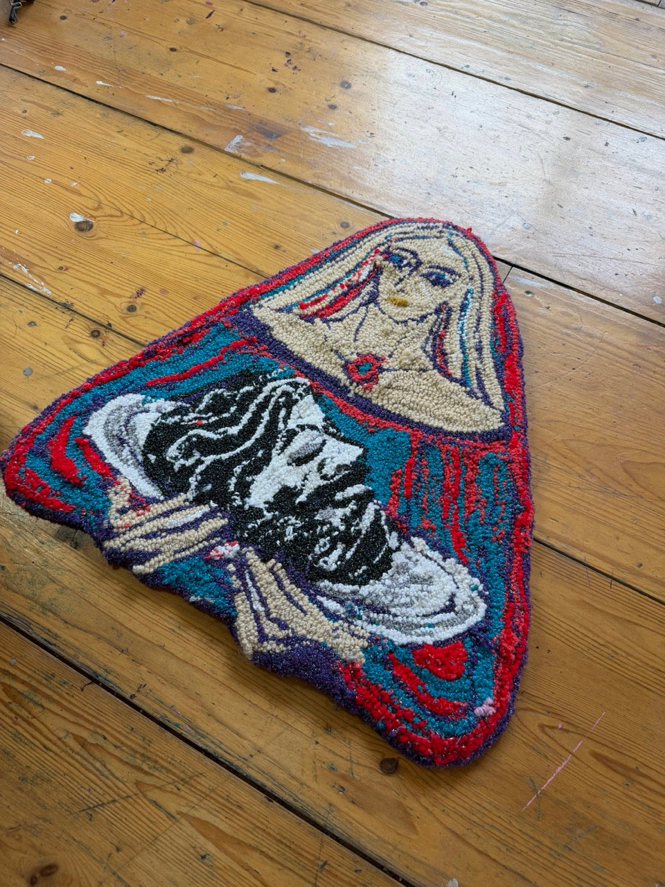 Decorative wall tapestry with a stylized face design on a wooden floor